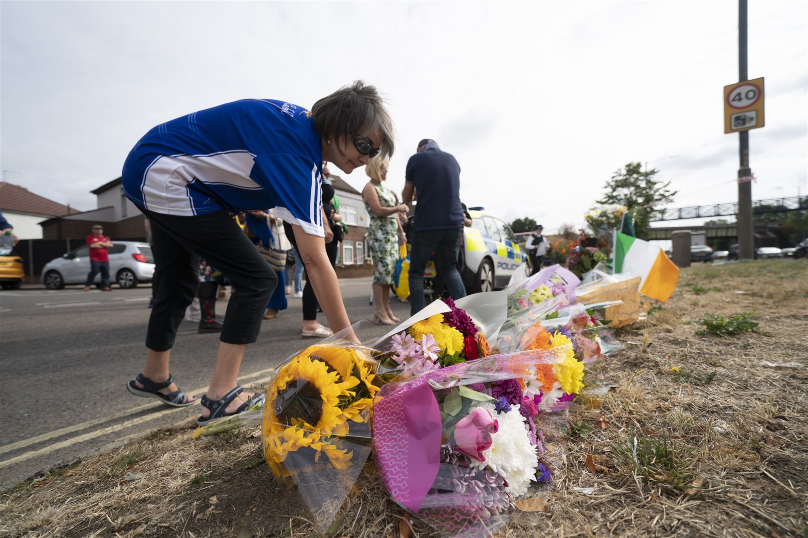 A woman lays flowers on Western Avenue Frontage Road in Greenford (Kirsty O’Connor/PA)