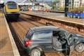 Car lands on train tracks at station