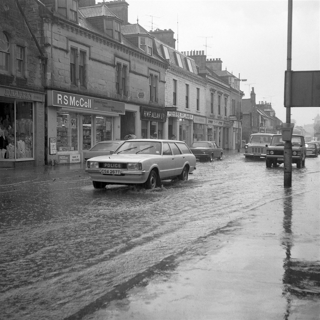 A police vehicle drives down a flooded Elgin High Street 40 years ago.