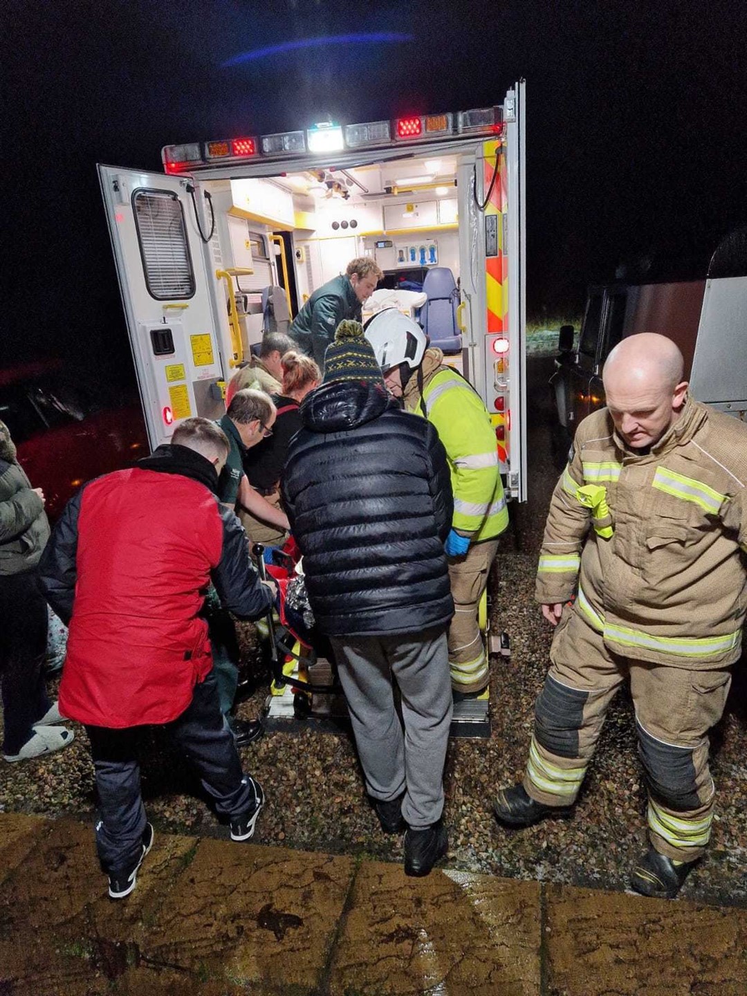 Ann Blackwood is helped into the back of an ambulance by firefighters, family and ambulance workers.