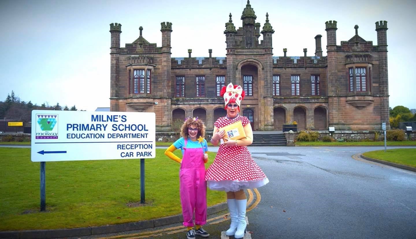 Out Of The Darkness Theatre Company's Dame Deanie and Fairy Firth outside Milne's Primary School, where they were delivering a copy of their DVD.