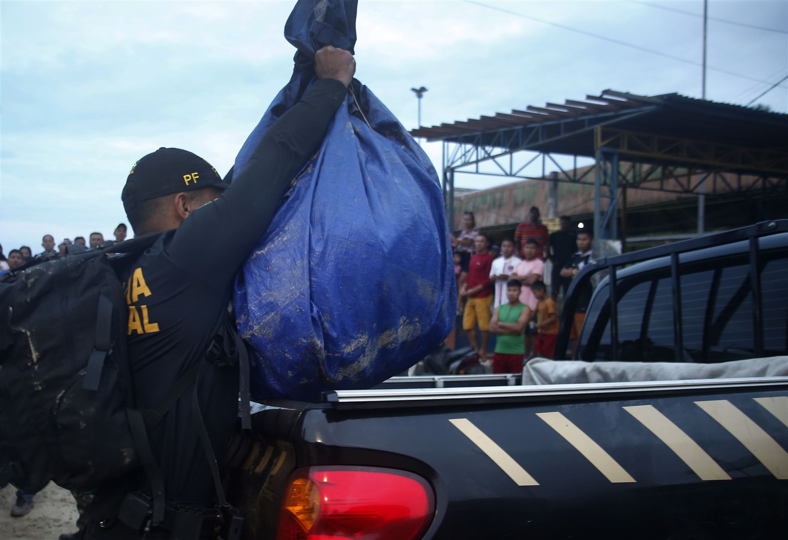A Federal Police officer loads a truck with items found during a search for the men (Edmar Barros/AP)