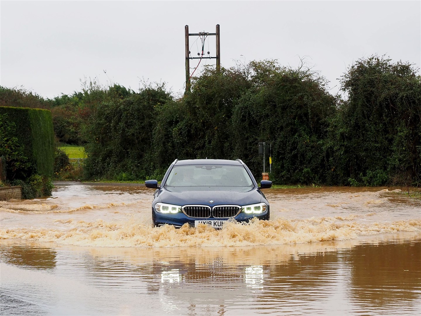 Vehicles drive through a flooded road in West Sussex following downpours caused by Storm Ciaran (Joe Sene/PA)