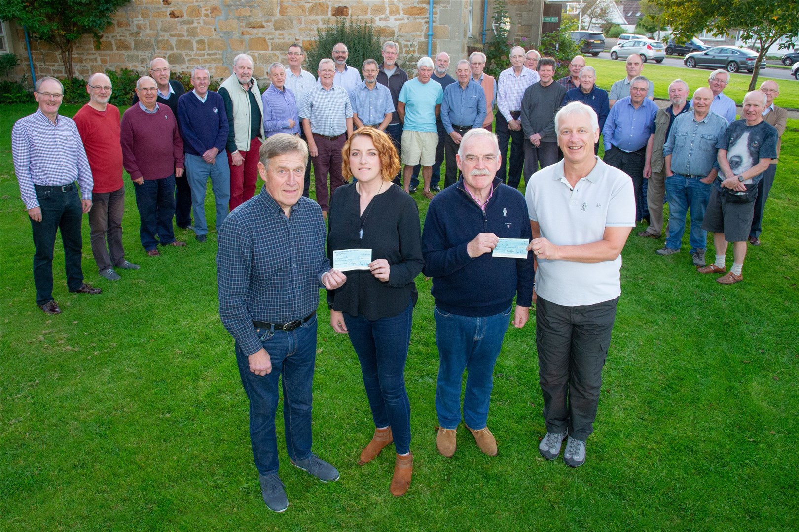 Glen Moray Male Voice Choir member Donald Brown (left) presents Gillian Pirie, of Moray Food Plus, with a cheque for £1000, while Angus Burnie (right) hands Dennis Thomson a cheque for £1500 for Prostrate Cancer UK. Picture: Daniel Forsyth.