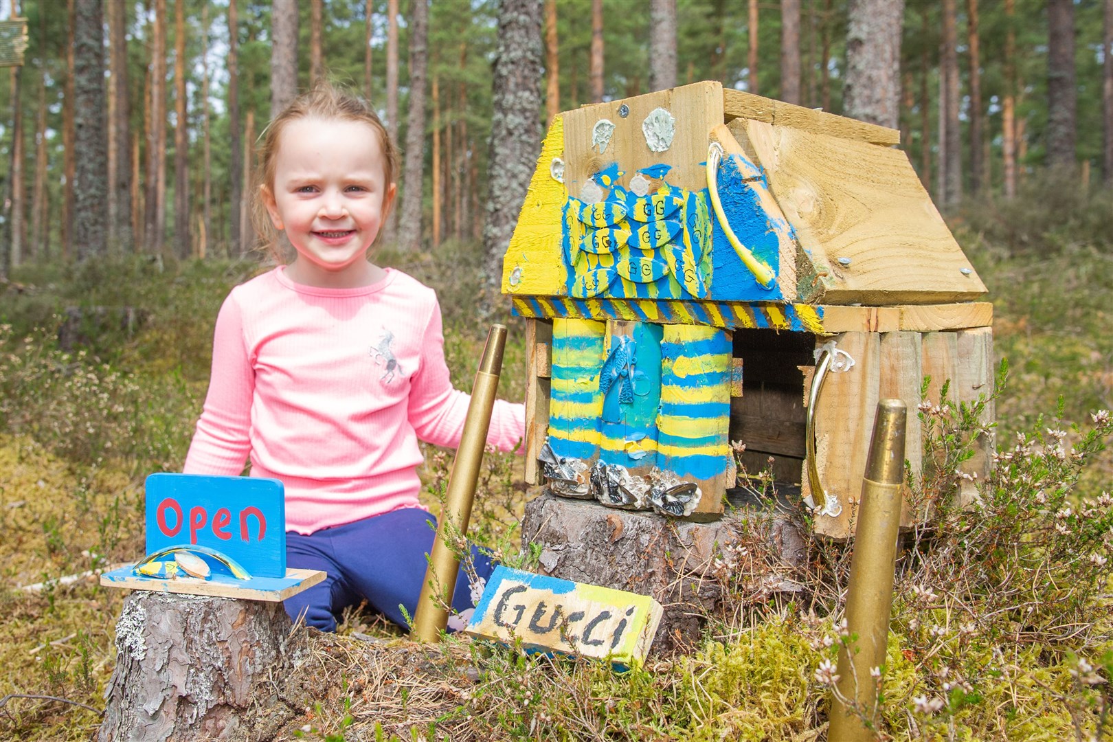 Mia Chilton takes a look at the Gucci store. A small village has been made out of wooden houses and household items in the Lossie Forest woodland. Picture: Daniel Forsyth.