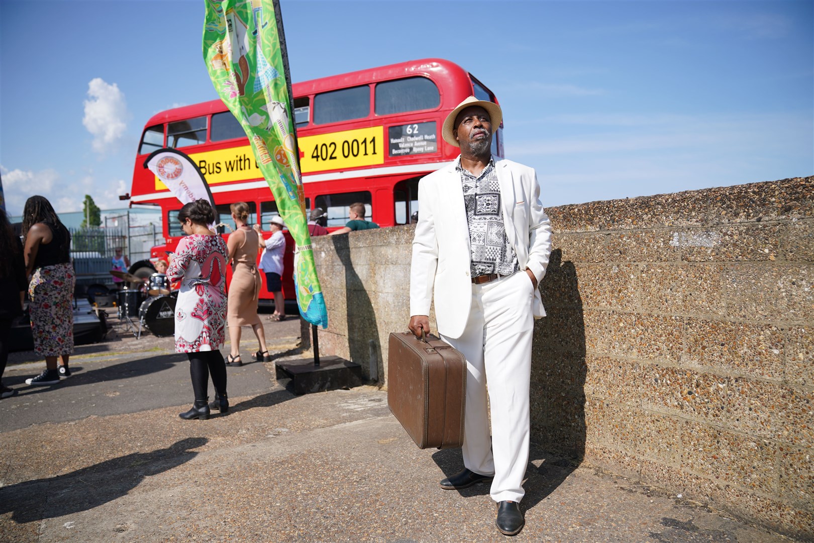 A man carries a single vintage suitcase to represent the journey many of the Windrush Generation made to answer the UK’s call for workers (Lucy North/PA)