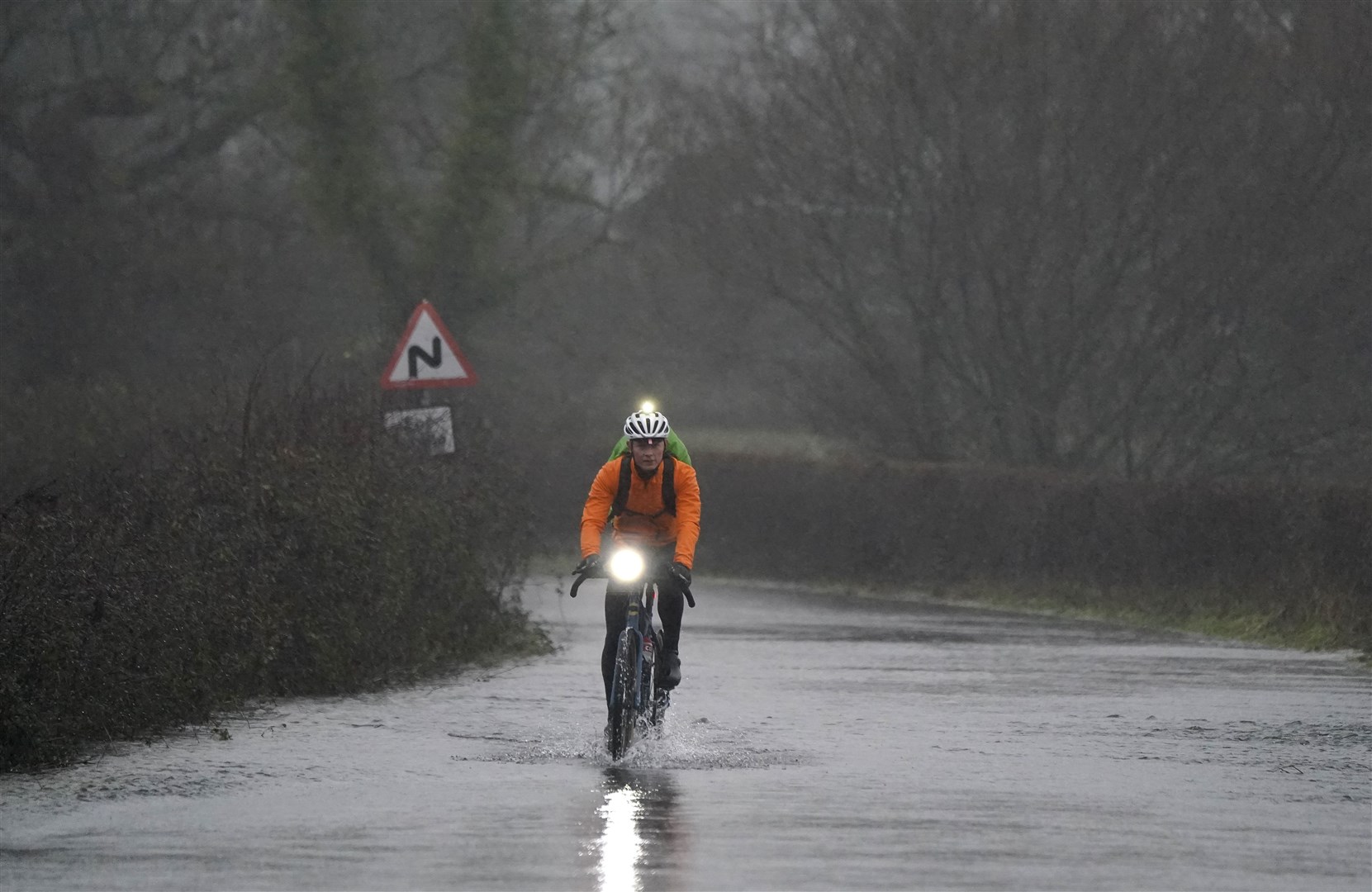A cyclist makes their way through flood water on Kent Lane, near to Ibsley in Hampshire (Andrew Matthews/PA)