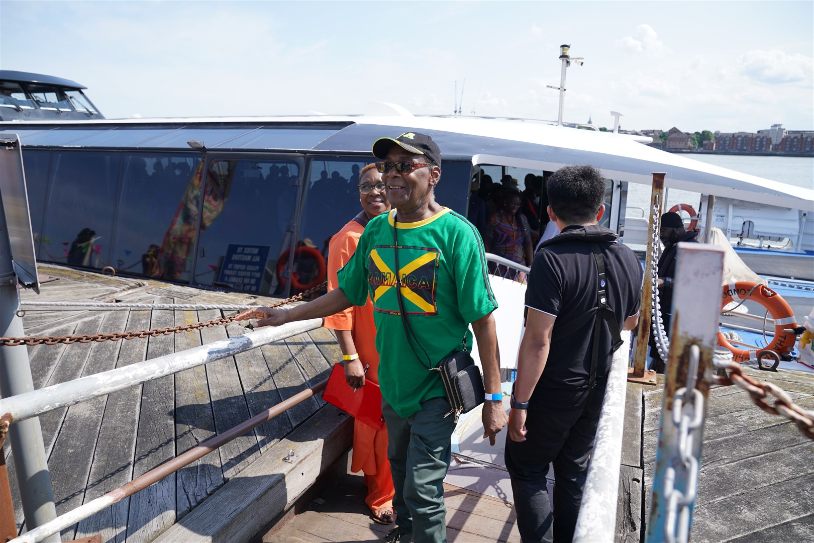 A man wears a T-shirt with the Jamaican flag as he disembarks (Lucy North/PA)