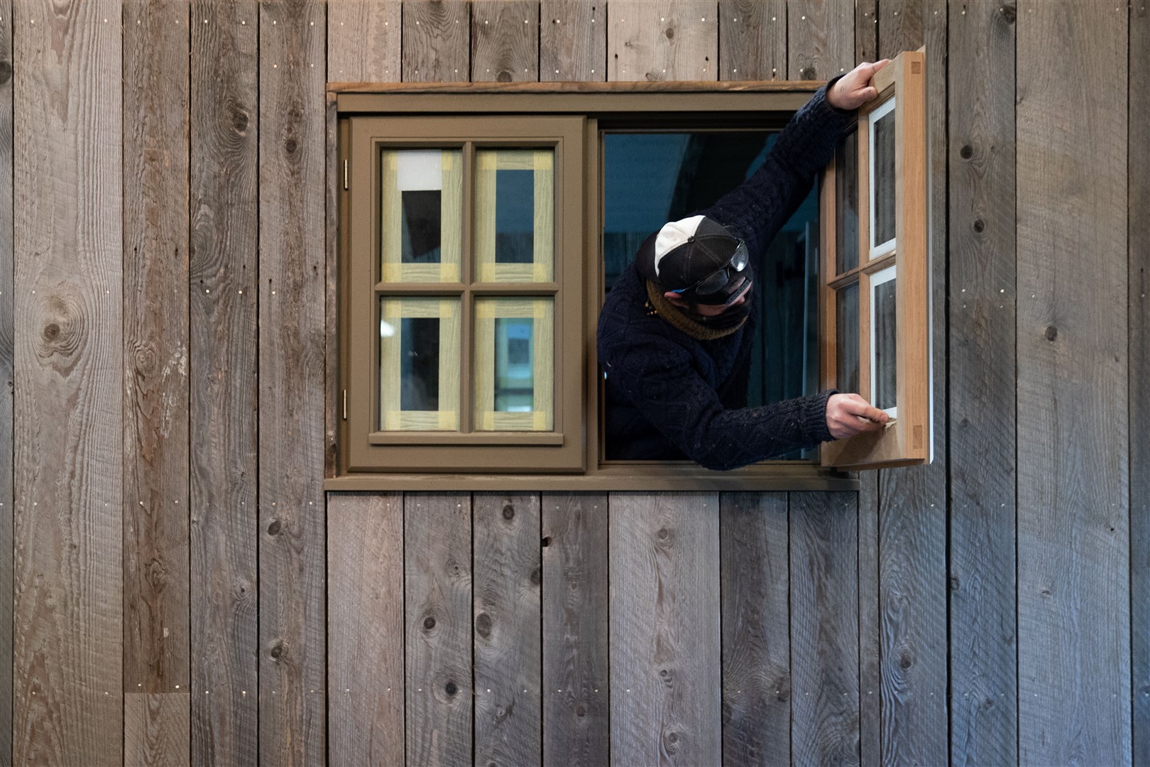 An employee removes tape from a window in a shepherd’s hut in the workshop of Plankbridge (Andrew Matthews/PA)