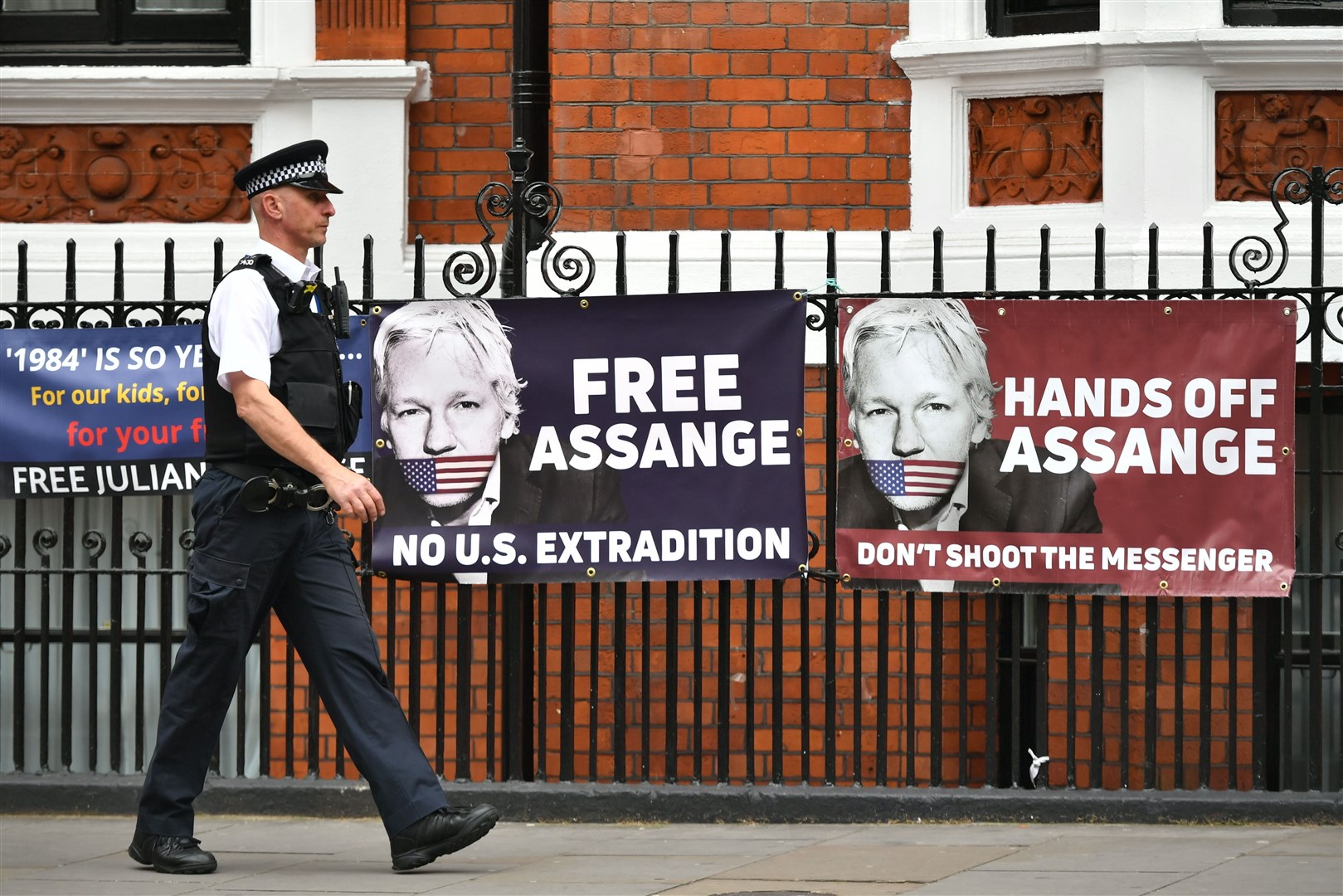 A police officer walks past the Ecuadorian embassy in London where Julian Assnge is holed up (Dominic Lipinski/PA)