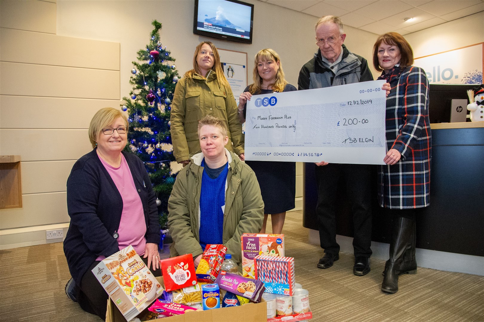 Mairi McCallum (front right), of Moray Food Plus, and Morag Malcolm, TSB community champion, as branch staff hand over a cheque and food box to Moray Food Plus. Picture: Daniel Forsyth.