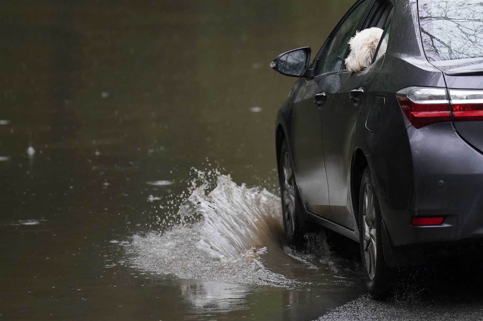 A car is driven through a flooded road in Faithlegg, Co. Waterford, Ireland, following Storm Babet (Niall Carson/PA)