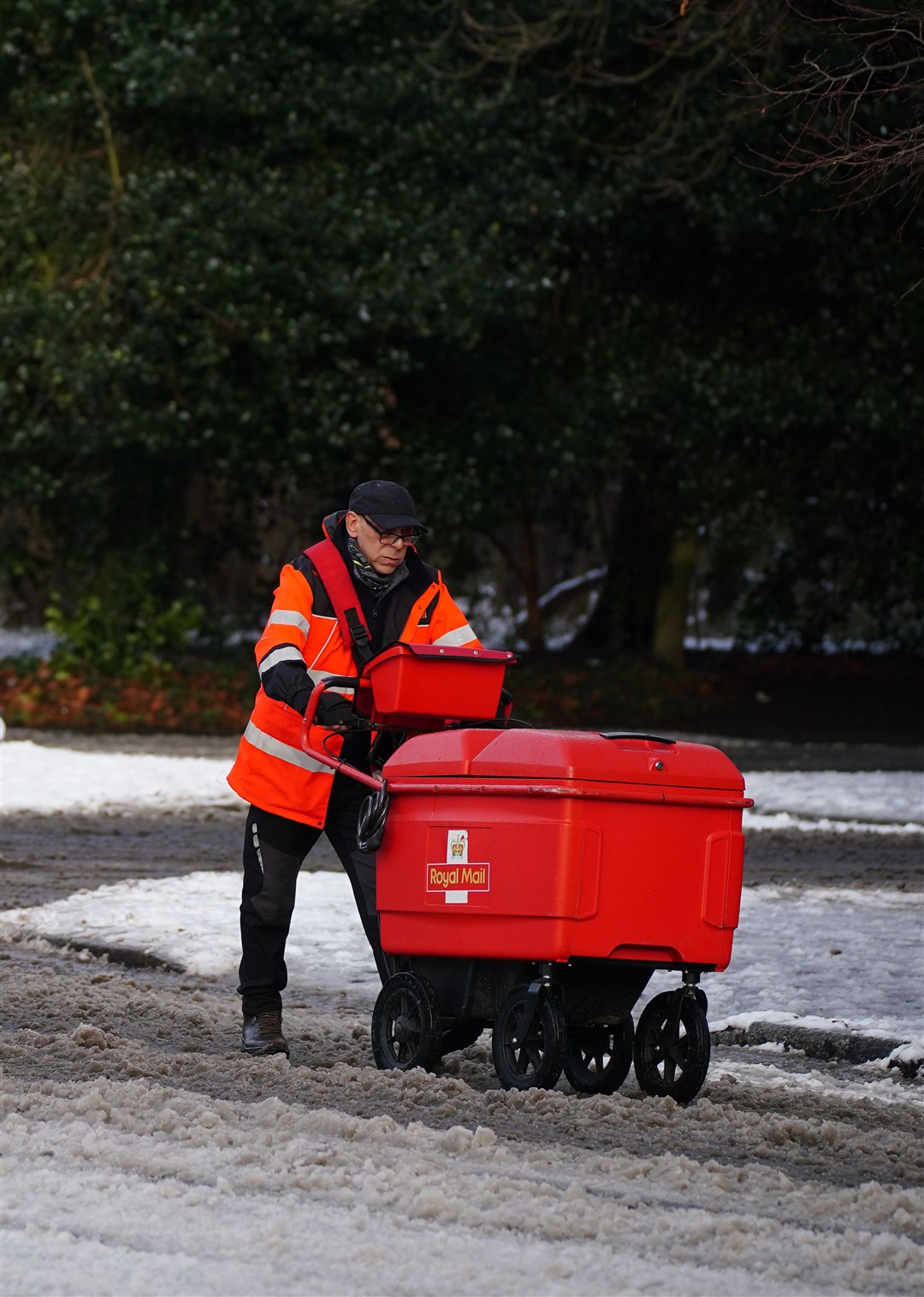 A postman battles through the snow in Sefton Park, Liverpool (Peter Byrne/PA)