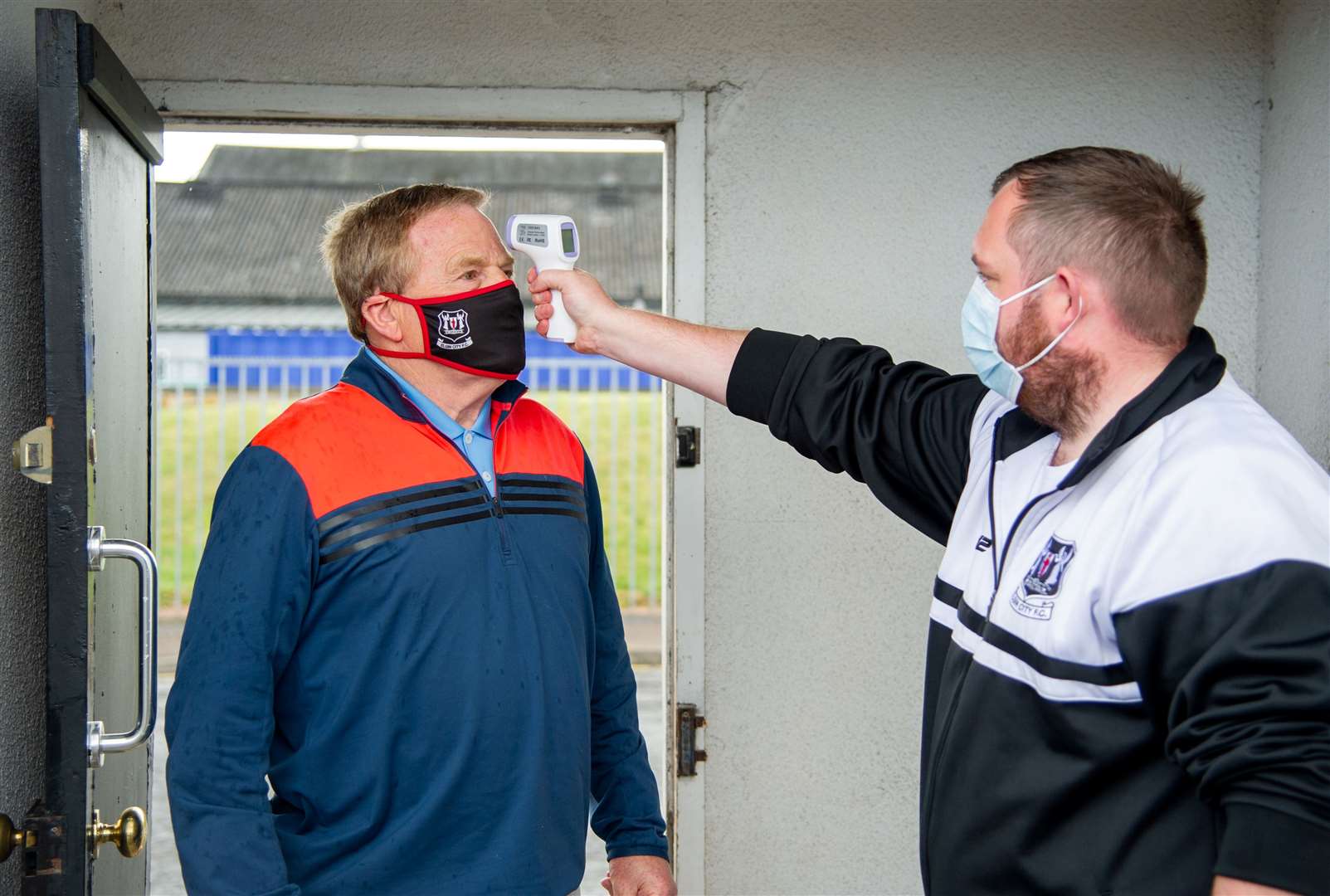 All part of the Covid-19 protocol at matches as Elgin City community football officer Craigh Stewart checks club chairman Graham Tatters' temperature on entry to the stadium. Picture: Daniel Forsyth..