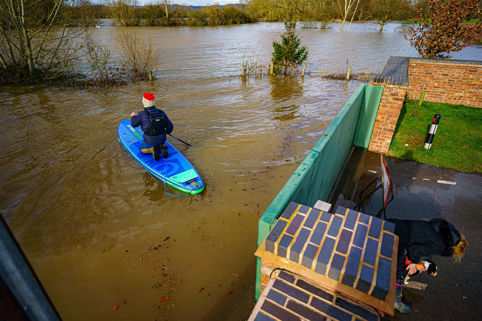 A man on a paddle-board makes his way along a flooded lane in Uckinghall, near Tewkesbury, Gloucestershire, in February (Ben Birchall/PA)