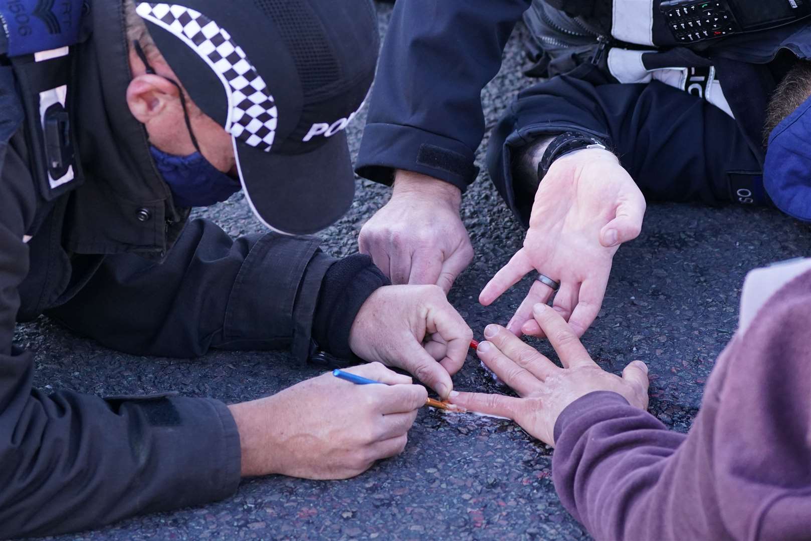 Police officers remove a protester glued to the road at an Insulate Britain roadblock on the M25 (PA)