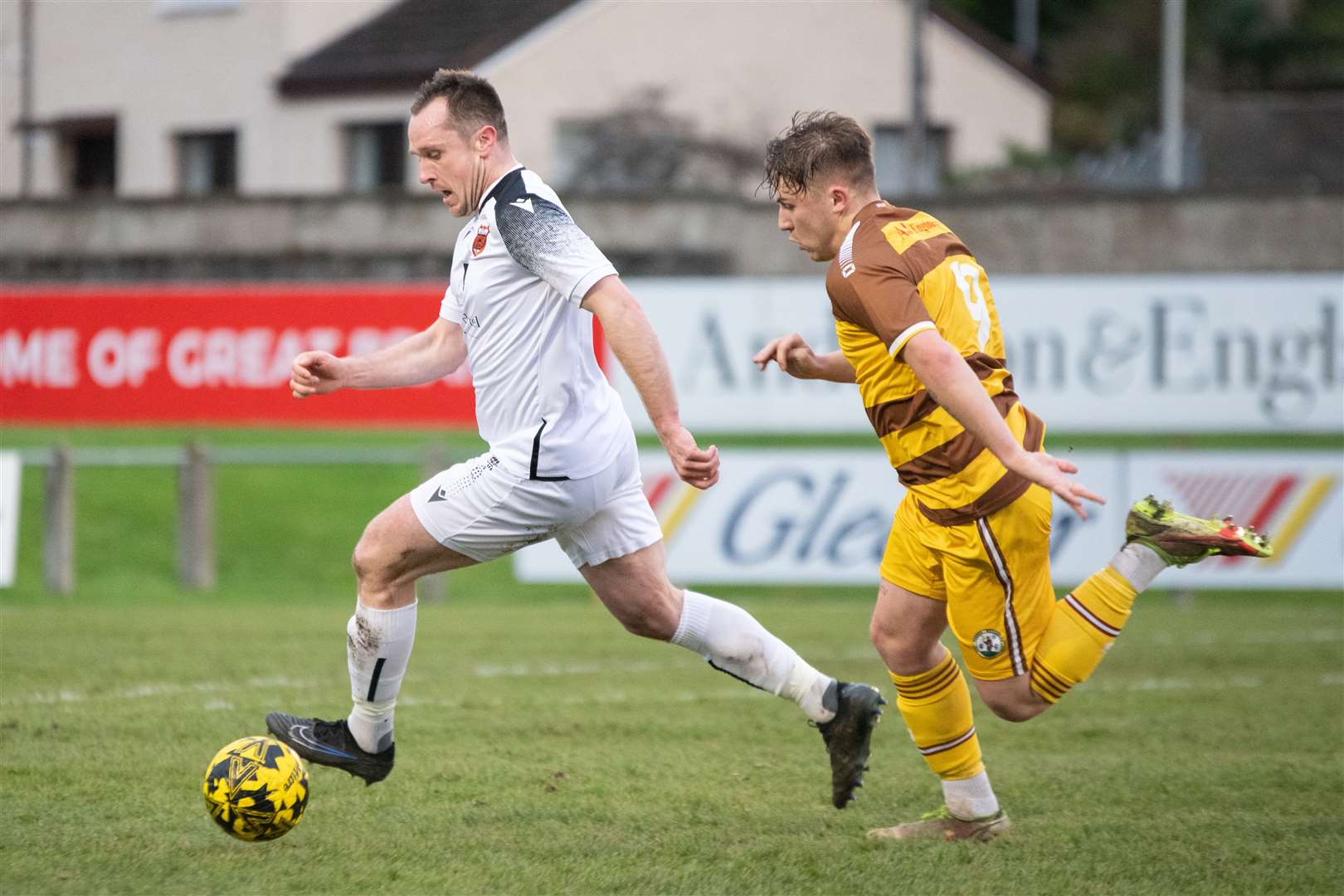 Rothes centre back Charlie MacDonald looks to play the ball away from Forres forward Shaun Morrison. ..Forres Mechanics FC (0) vs Rothes FC (1) - Highland Football League 23/24 - Mosset Park, Forres 25/11/2023...Picture: Daniel Forsyth..