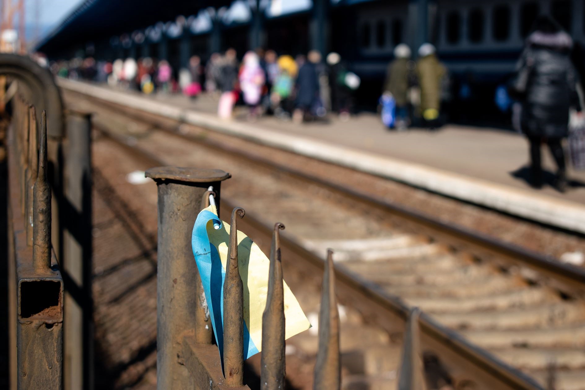 Ukrainian refugees leave Ukraine. Railway stations of Western Ukraine are filled with migrants. Ukrainian Flag on a fence of the station. Humanitarian catastrophe. Refugees got off a train in Uzhhorod