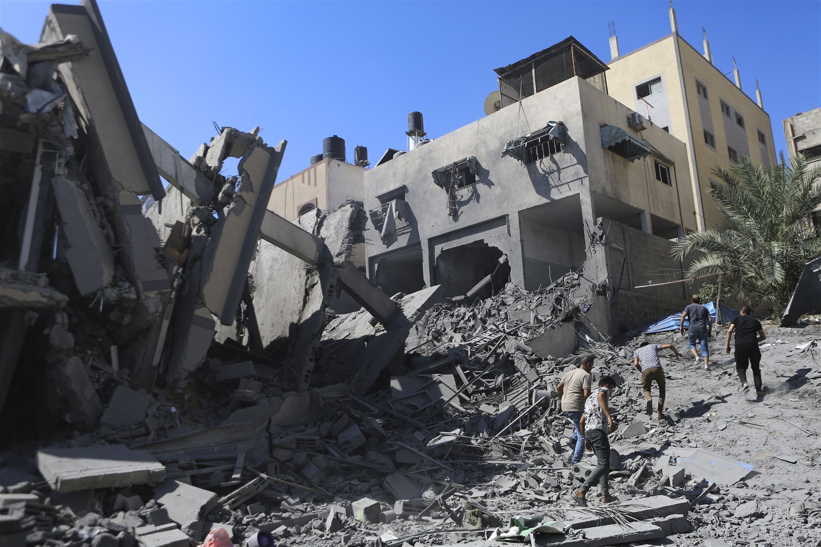 Palestinians inspect the damage of a destroyed building following Israeli air strikes on Gaza City (Abed Khaled/AP)