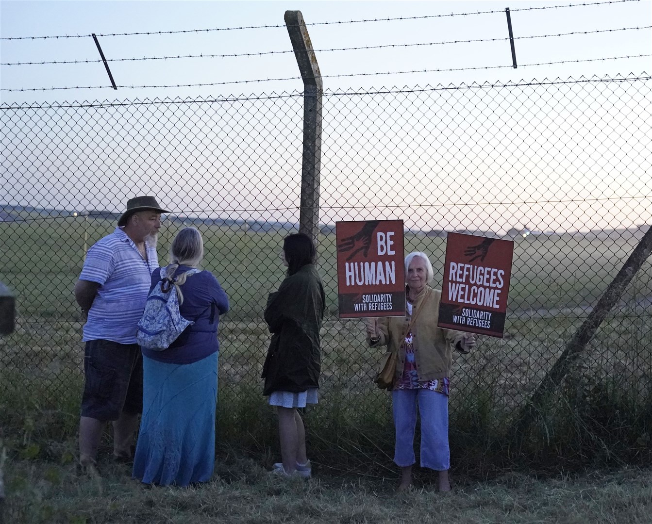 Protesters at the perimeter of MoD Boscombe Down, near Salisbury, where a Boeing 767 aircraft was believed to be the plane tasked to take asylum seekers from the UK to Rwanda (Andrew Matthews/PA)