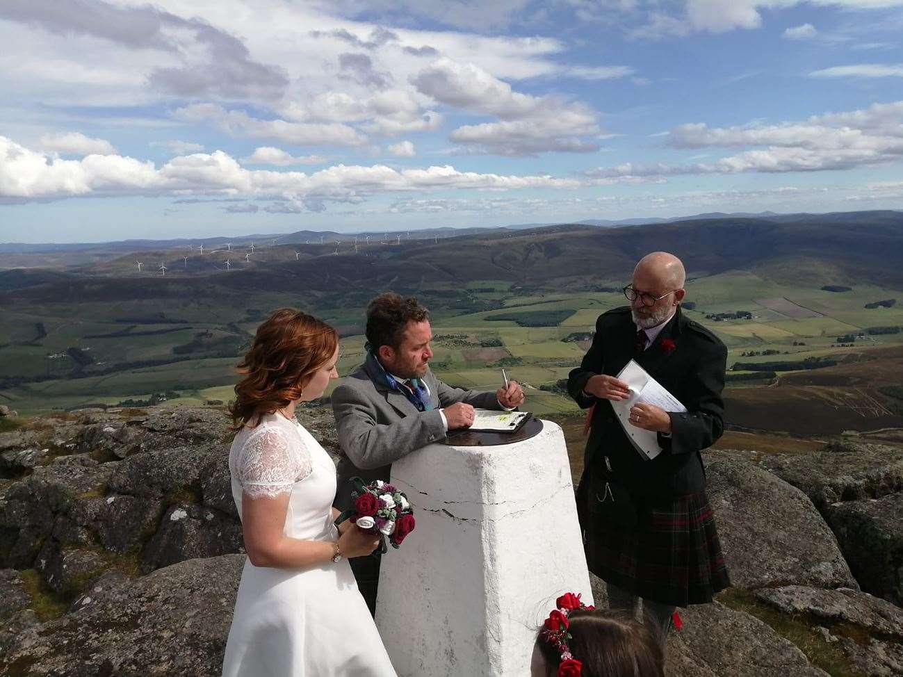 The happy couple sign the marriage certificate on the trig point.