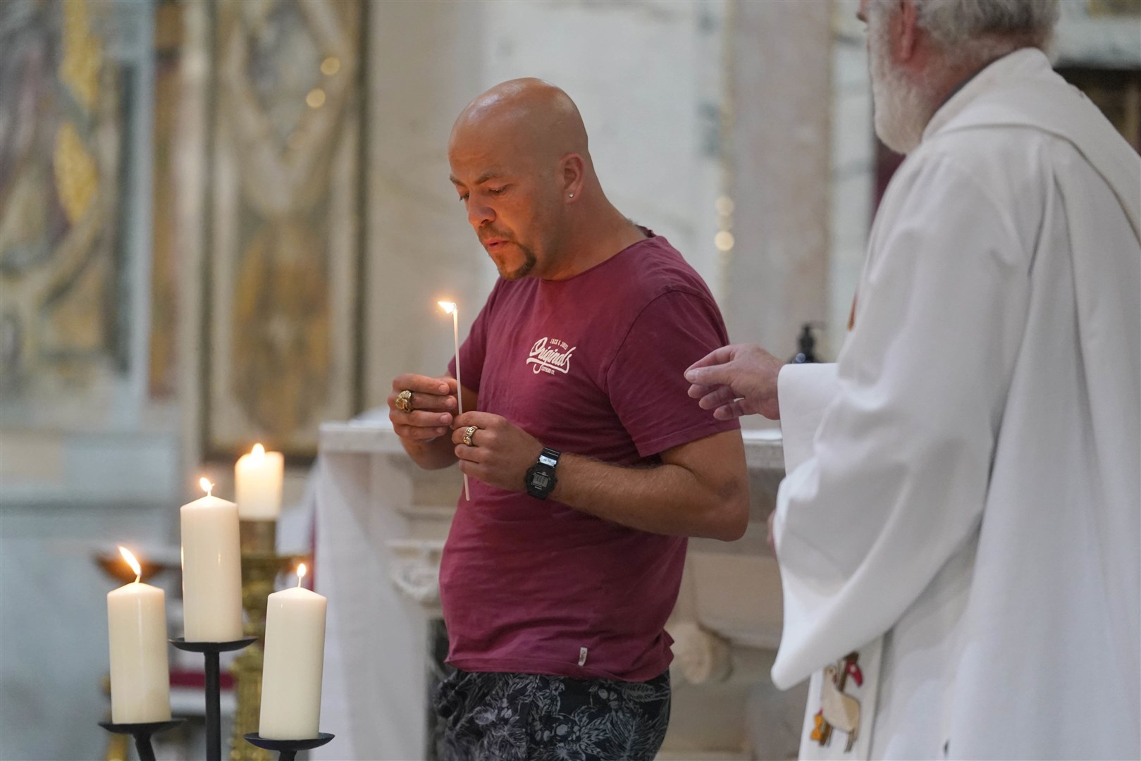 Thomas O’Reilly’s brother Michael lights a candle during a vigil at St John the Baptist Church in Cashel (Brian Lawless/PA)