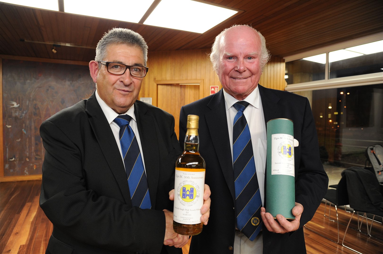 Graeme "Tiger" Porter presents Mike Christie with a bottle of whisky to commemorate his 50 years service with Elgin Boys Club.