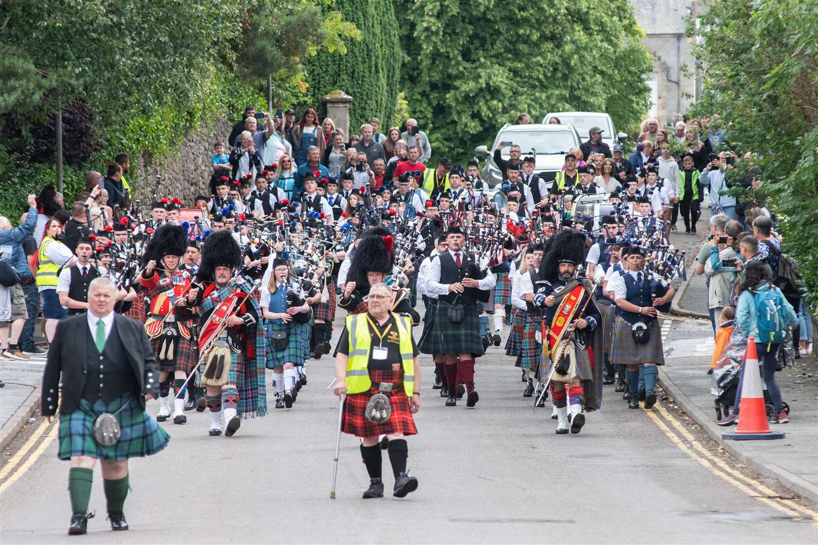 The Massed Pipes and Drums march down Queen's Road to the playground...77th Aberlour Strathspey Highland Games held on Saturday 6th August 2022...Picture: Daniel Forsyth..
