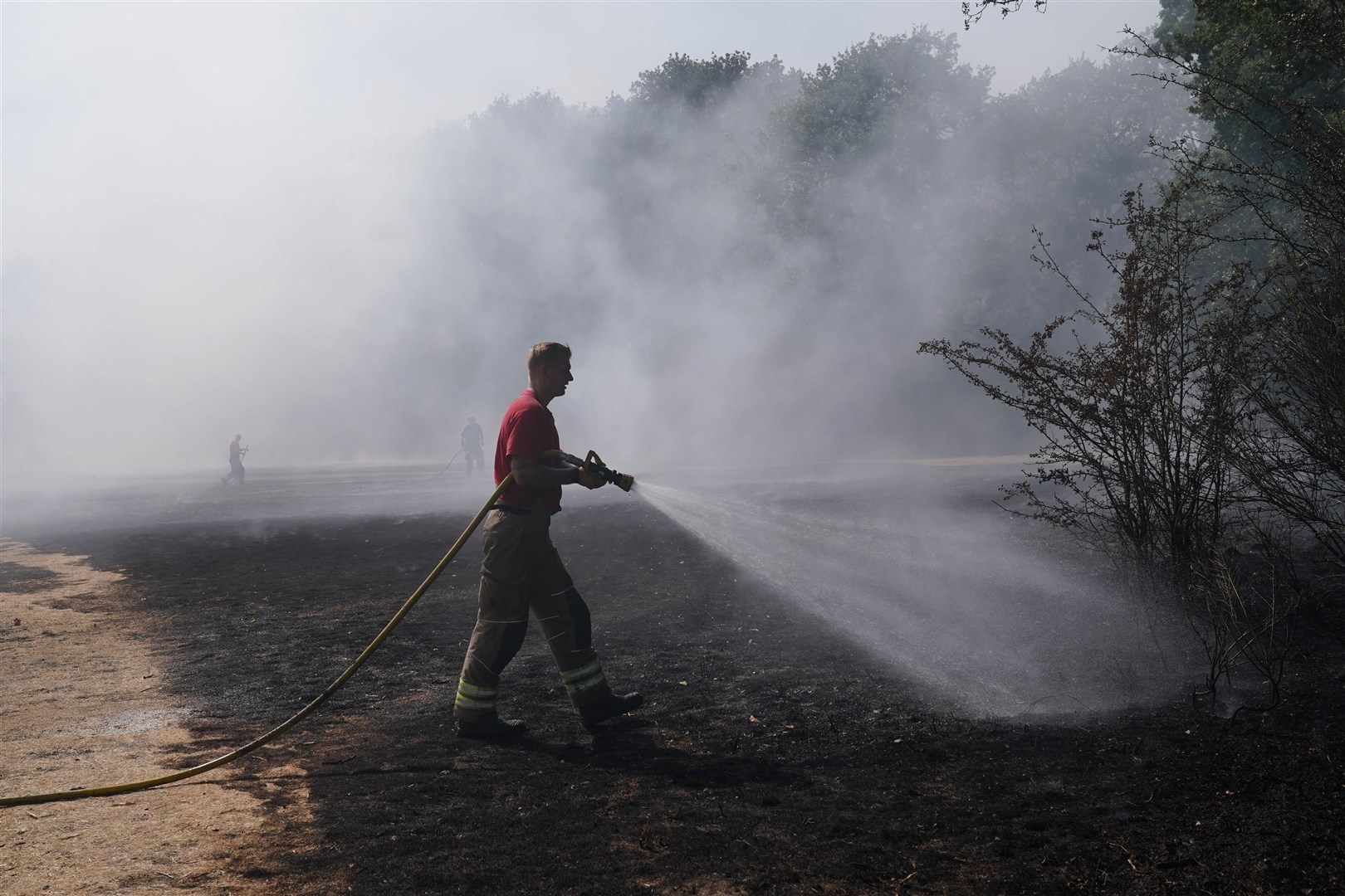 A firefighter dampens down a grass fire at Leyton Flats in east London (Yui Mok).