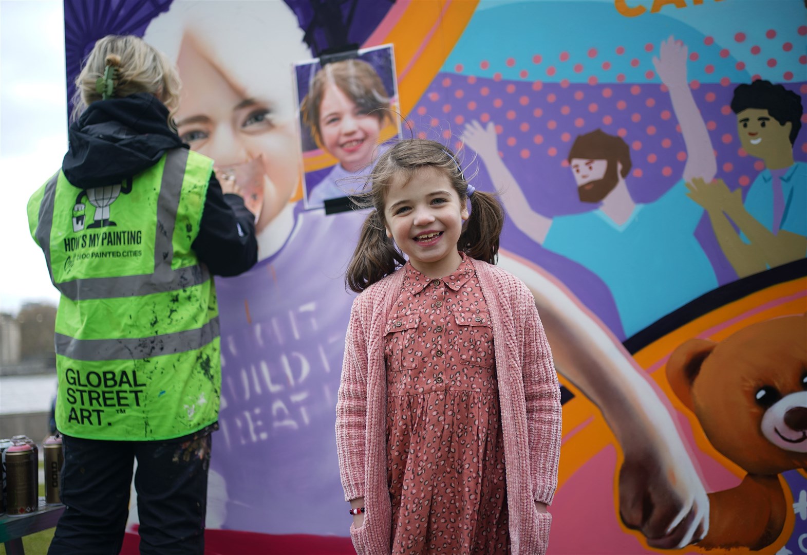 Six-year-old Sienna Halls, from Ruislip in London, next to an 8ft mural at Potters Fields Park in London (Yui Mok/PA)