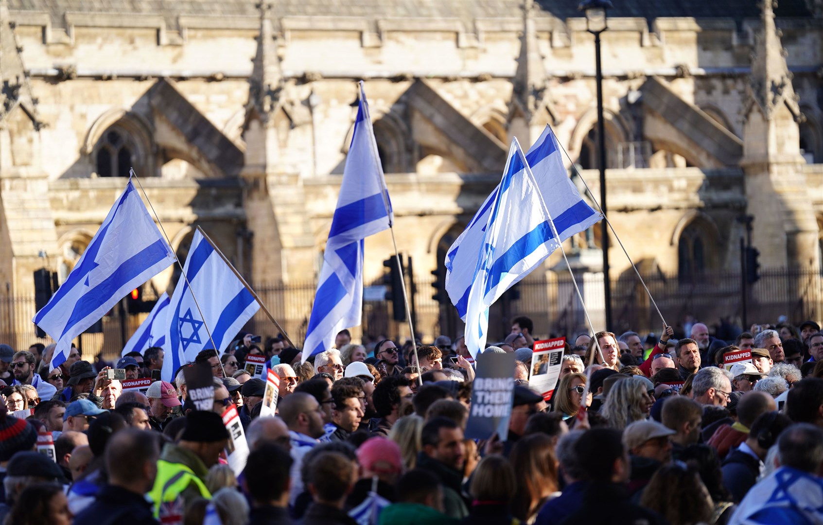 People wave Israeli flags at the vigil in Parliament Square (James Manning/PA)