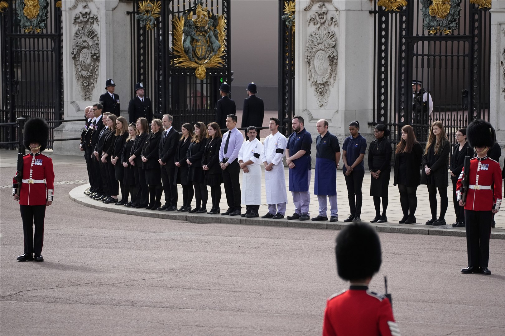 Buckingham Palace staff stand outside its gates (Christophe Ena/PA)