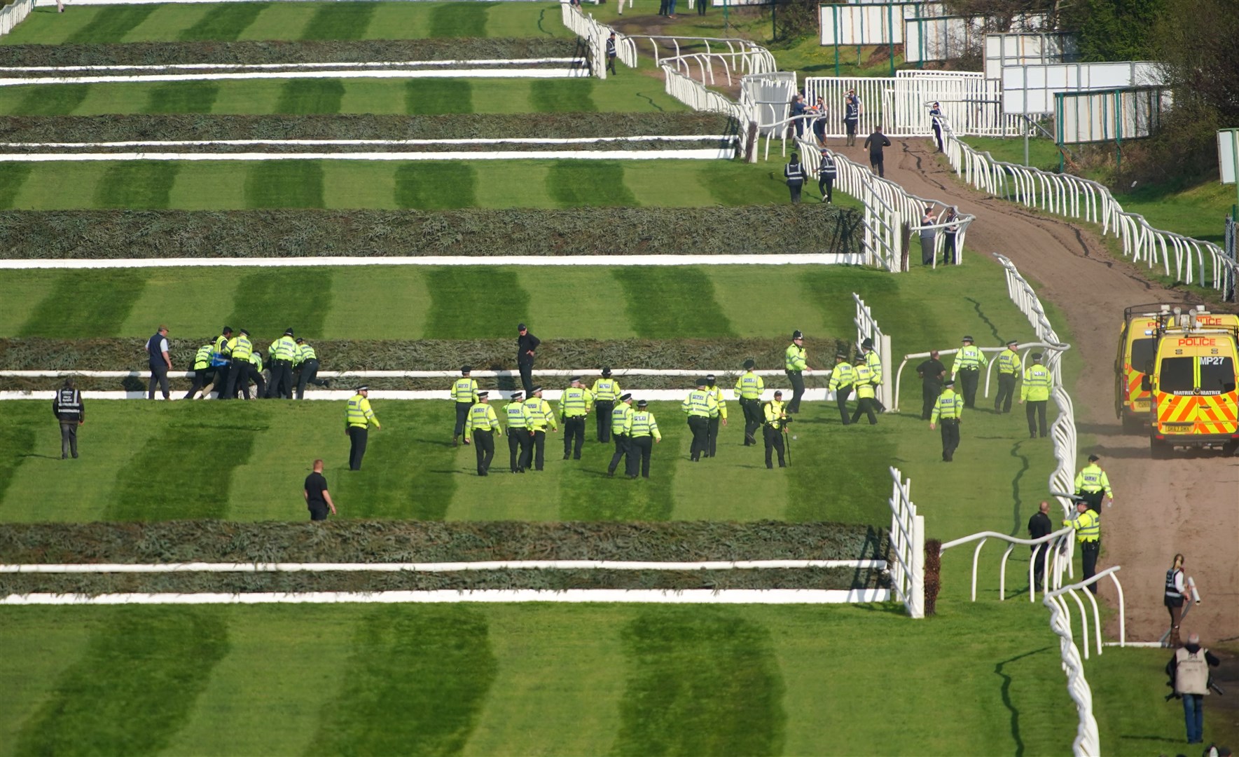 Police officers respond to Animal Rising activists attempting to invade the race course ahead of the Grand National on Saturday (PA)