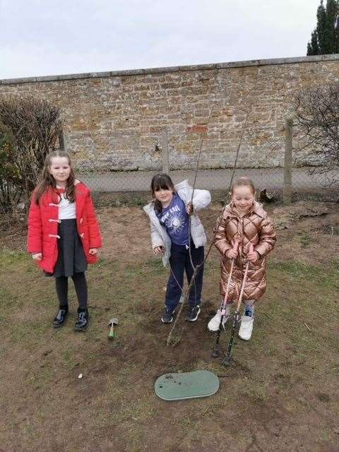From left: Iris Stewart P4 Eco Committee member, Bronwyn Atkinson and Esme Ralph both from P2 helping to plant one of the trees.