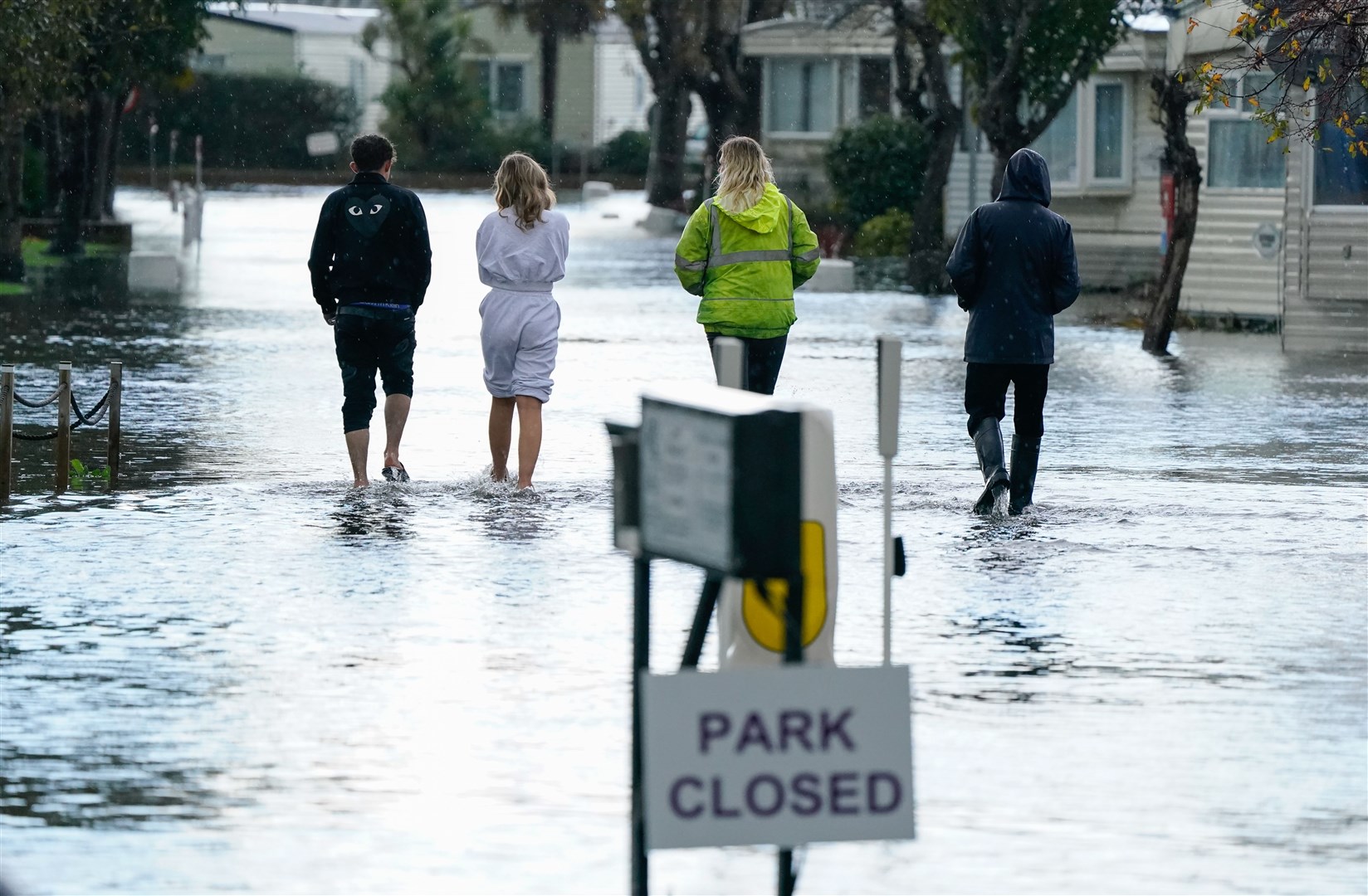 People walk through floodwater as they make their way into the Riverside caravan centre in Bognor Regis (Andrew Matthews/PA)