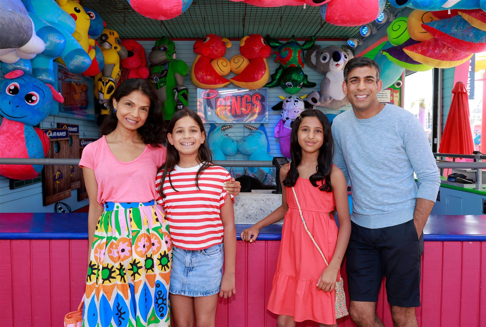 Akshata Murty, Krishna, Anoushka and Rishi Sunak pose in front of a ring-toss stall on Santa Monica Pier (Emma McIntyre/PA)