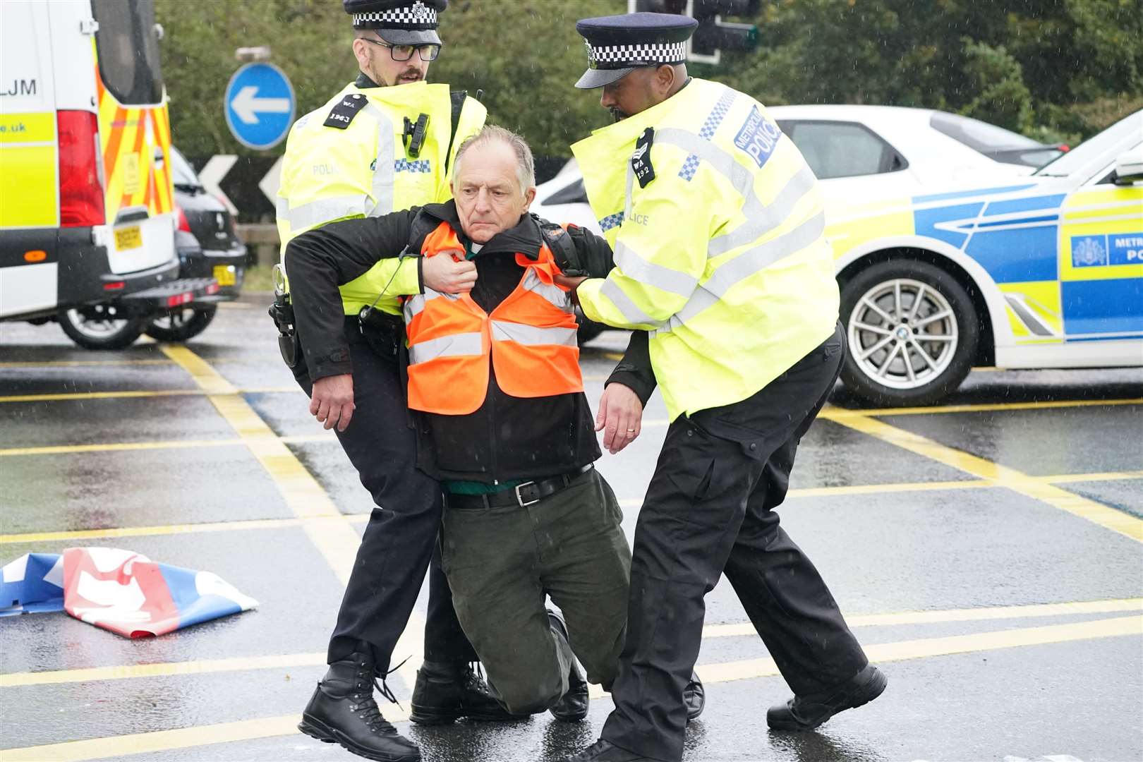 Police officers detain a protester from Insulate Britain occupying a roundabout leading from the M25 motorway to Heathrow Airport in London (Steve Parsons/PA)