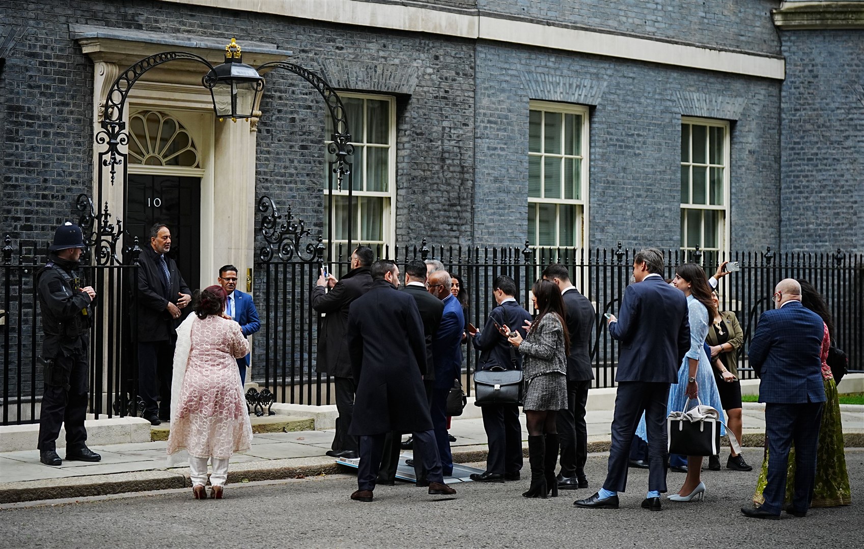 Members of the Muslim community wait to have their picture taken in front of 10 Downing Street’s door as they arrive for an Eid reception (Aaron Chown/PA)