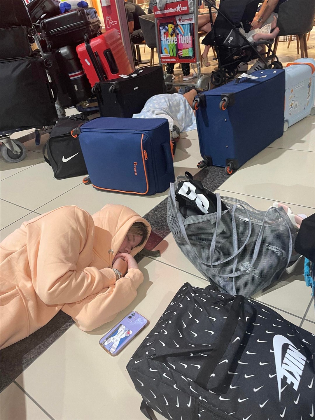 People sleeping on the floor in the airport.