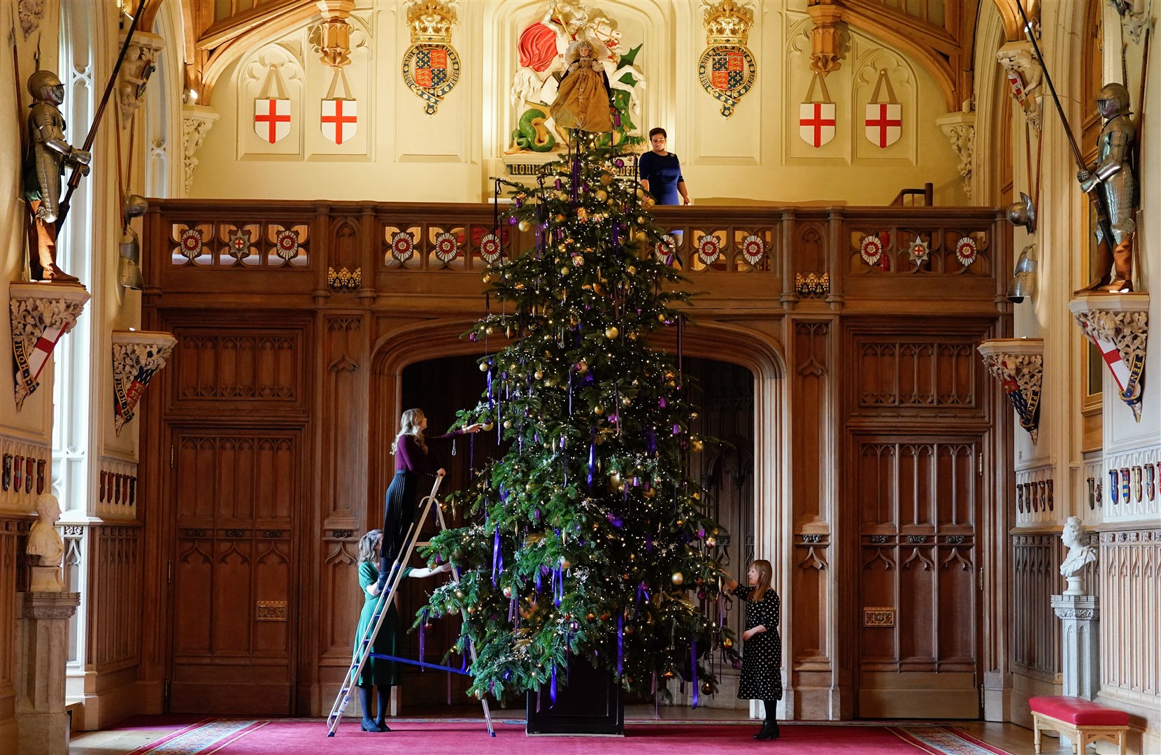 Members of the Royal Collection Trust put the finishing touches to a 20-foot-high Nordmann Fir Christmas tree in St George’s Hall, Windsor Castle (Andrew Matthews/PA)