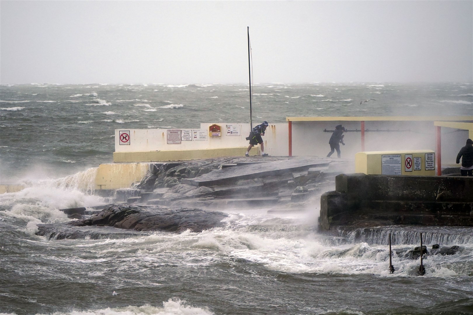 People walking away after taking photos of high waves at Salthill, Galway, during Storm Isha (Niall Carson/PA)