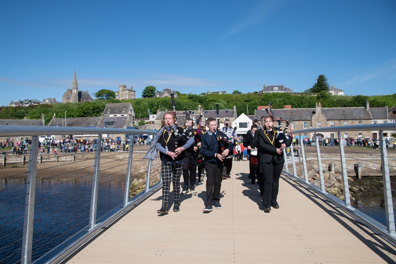 The Lossiemouth High School pipe band leads guests across the bridge. Picture: Daniel Forsyth