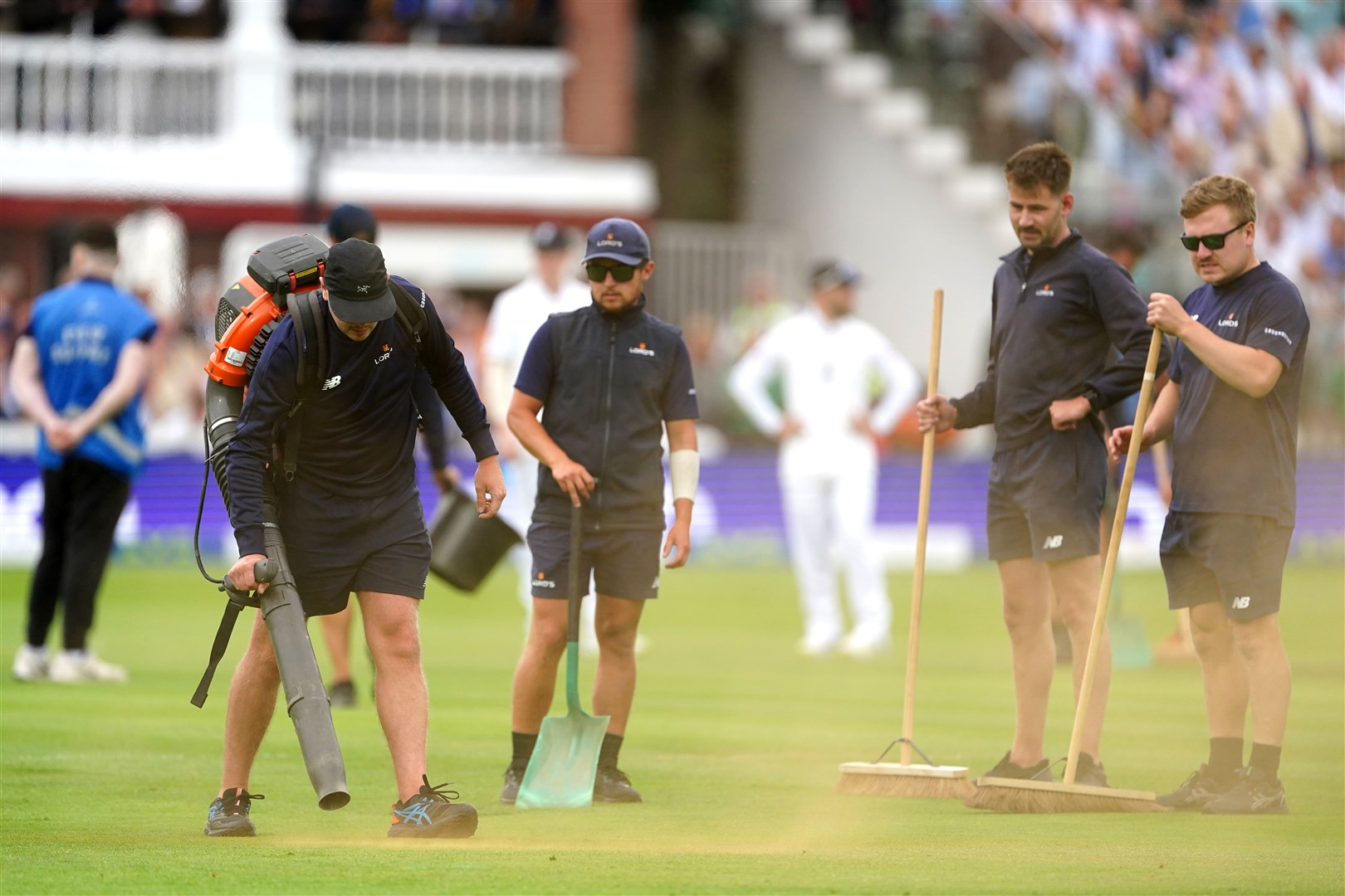 Ground staff cleaning up orange powder thrown by Just Stop Oil protesters during day one of the second Ashes Test match at Lord’s (PA)