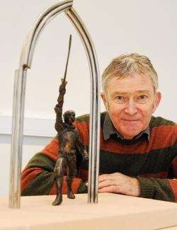 David Annand crouches beside a much smaller version of his Wolf of Badenoch sculpture.