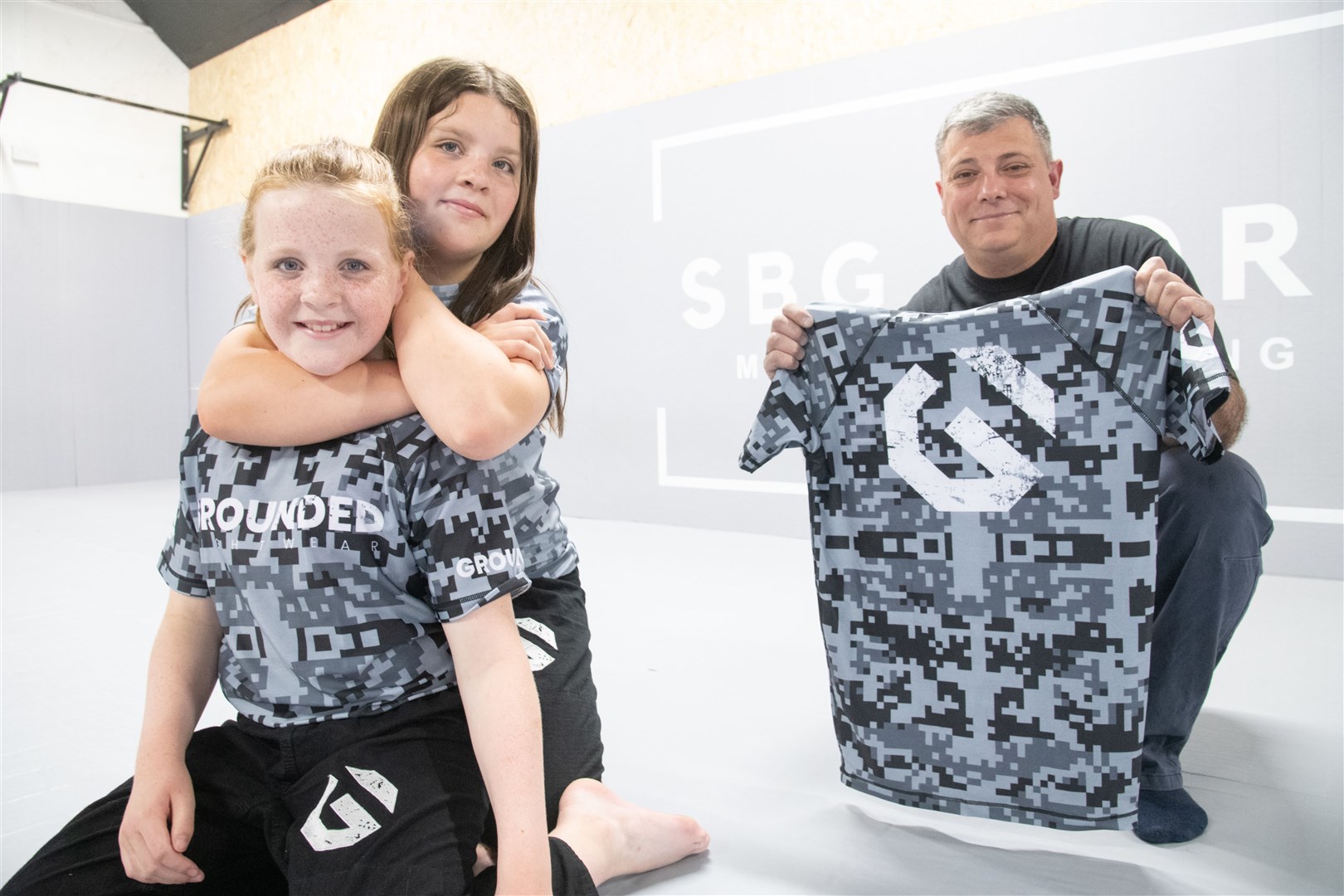 Sisters Izzy (front) and Niamh (front back) have seen 45 of their rash guards bought by local business owner Miguel Lima (right). Picture: Daniel Forsyth