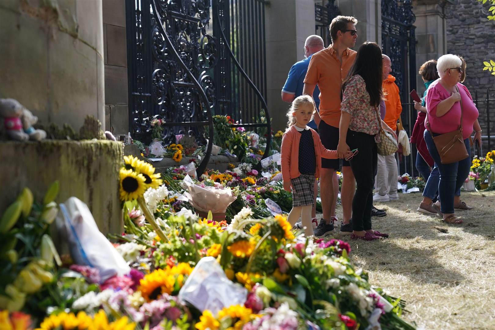 Members of the public view messages and flowers at the Palace of Holyroodhouse in Edinburgh ahead of the procession’s arrival (Jacob King/PA)