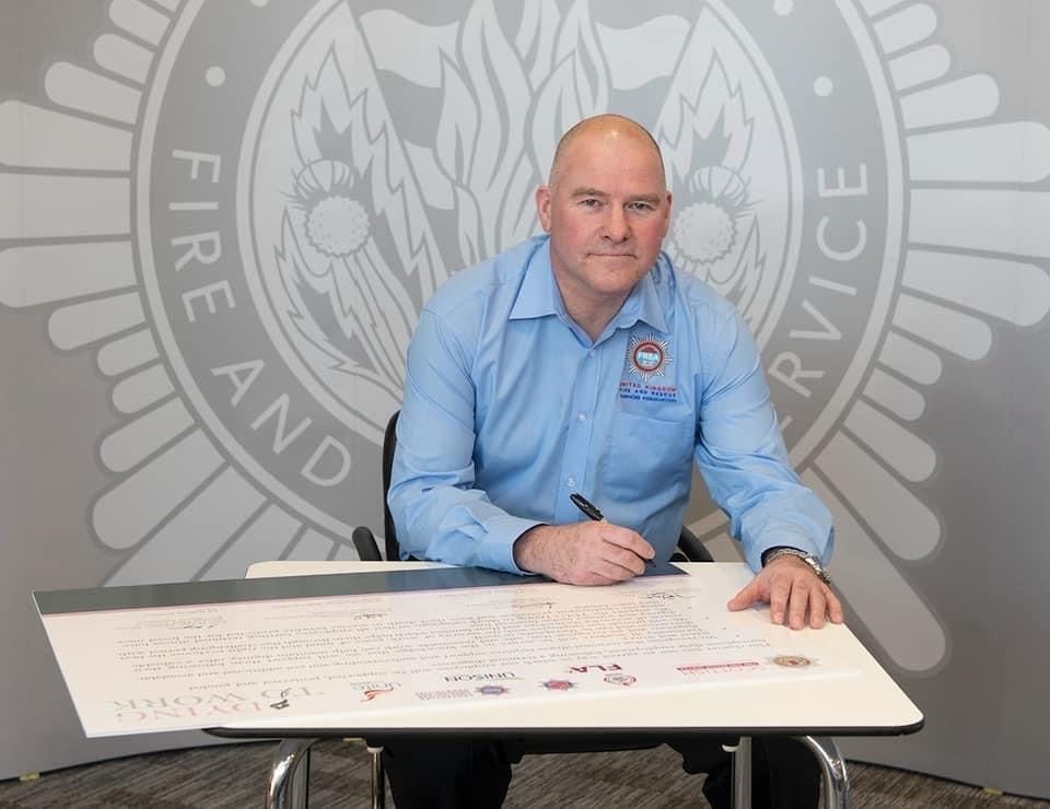 Fochabers firefighter Dave Crawford signs the Dying to Work Charter on behalf of the FRSA union.