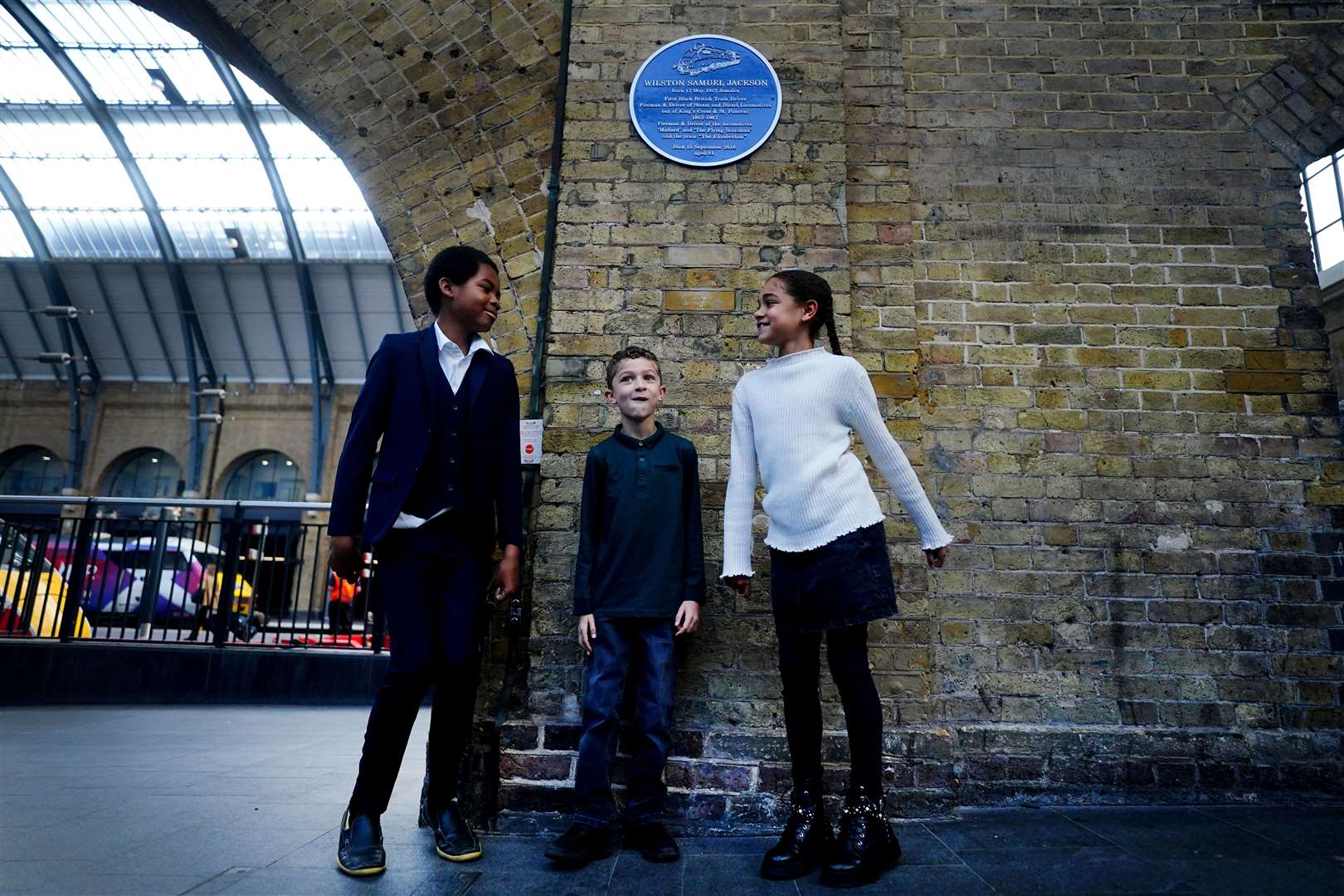 Josiah Jackson, Lawrence Hollingsworth and Sofia Hollingsworth stand below a plaque to commemorate their great grandfather Wilston Samuel Jackson (Victoria Jones/PA)