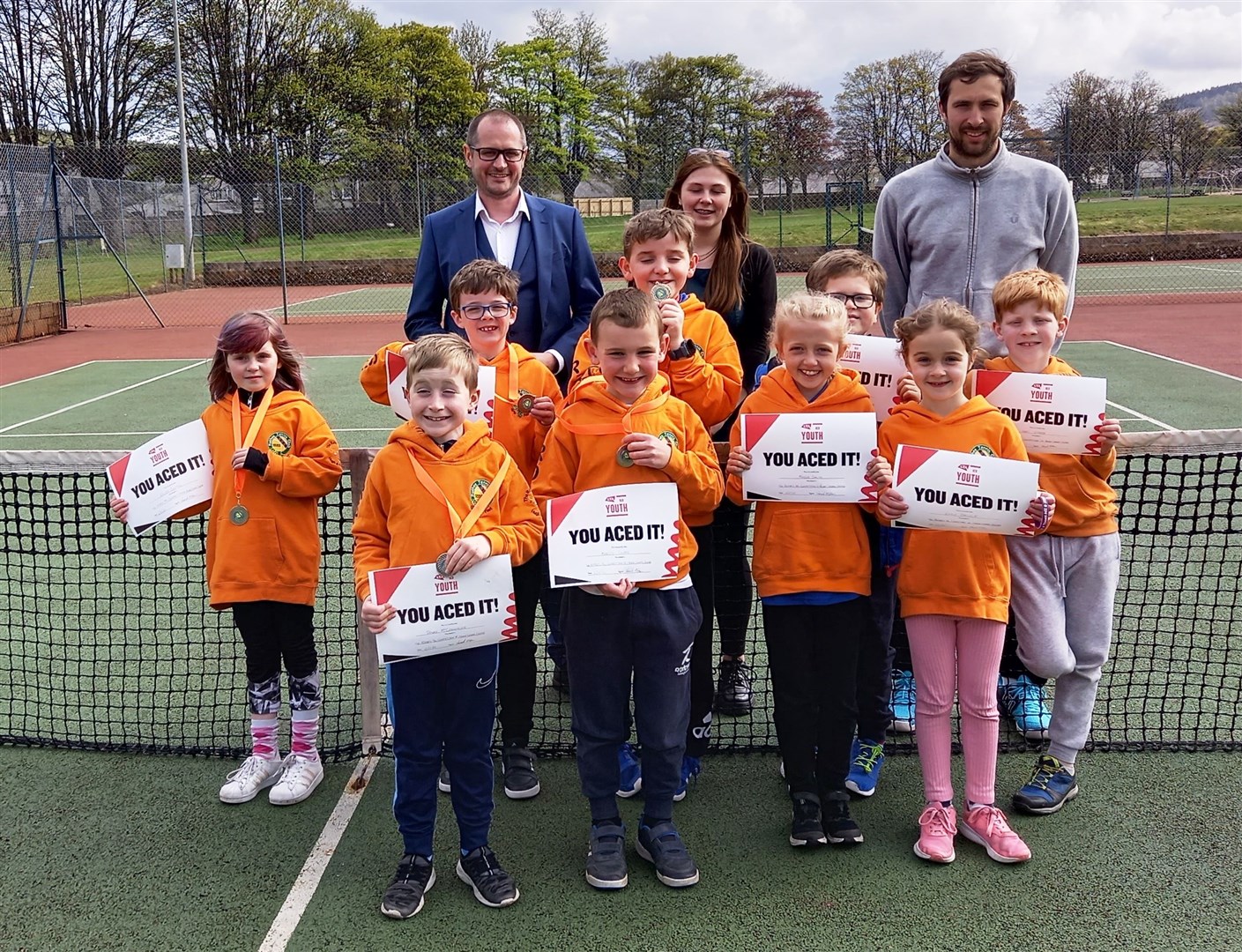 Pictured at the Rothes tennis tourney are, from left: Kevin Herbert and Jasmin Campbell from competition sponsors Rothes Pharmacy) and coach Stephen Anniss with the children who took part.