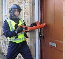 A police officer smashes in a door during a raid in Elgin.